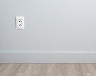 White vertical outlet on a white wall with wooden floors