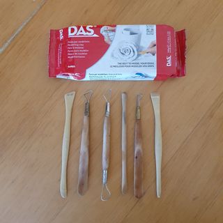 A flat lay of a pack of air dry clay and pottery tools