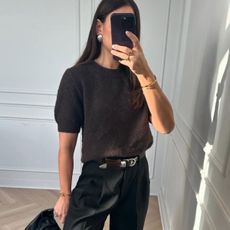 Woman wears brown short sleeve jumper, black tailored trousers