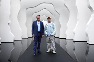Image of David Kohler and Daniel Arsham at the Divided Layers installation, grey pathway, reflective floor, white layered cave like structure