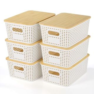 Six small white perforated storage baskets with light bamboo lids stacked in towers of three