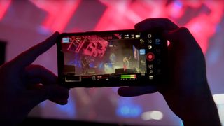 Still from a blackmagic design youtube video showing someone holding a phone up to a band on stage