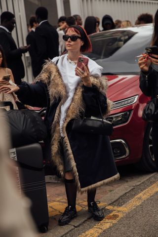 woman wearing top, faux fur coats, knee-high socks, and loafers