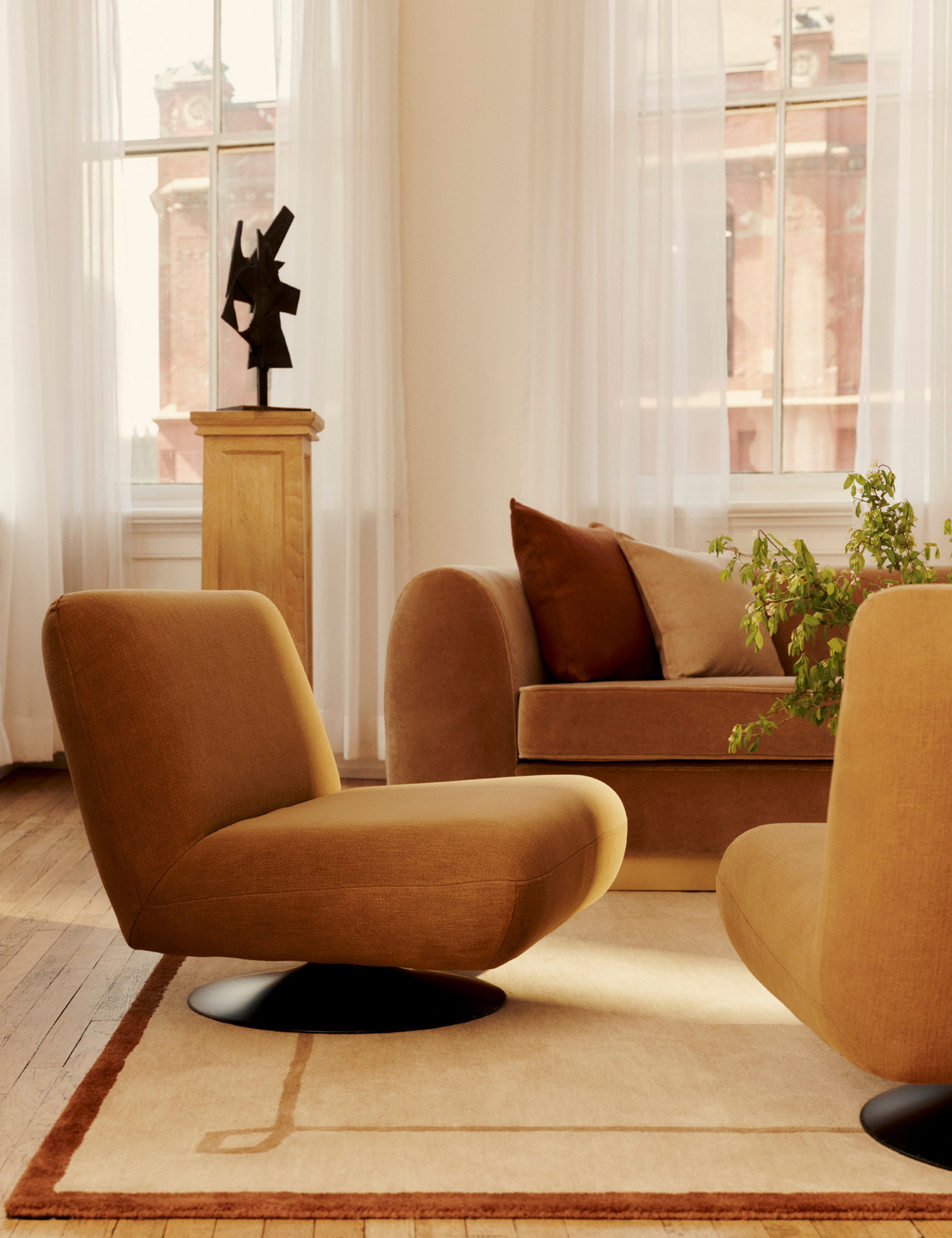 Modern NYC living room featuring low-slung ochre accent chairs and a coordinating mid-century sofa, anchored by a vintage-inspired rug by Nate Berkus for Rugs USA