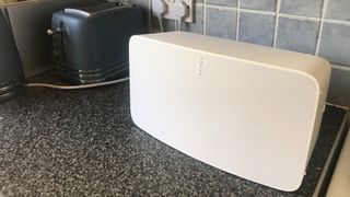 The Sonos Five speaker in white on a grey kitchen countertop