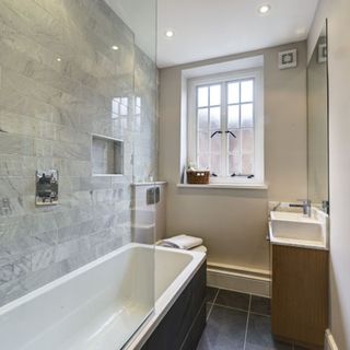 bathroom with bathtub wash basin white window and grey tiles wall