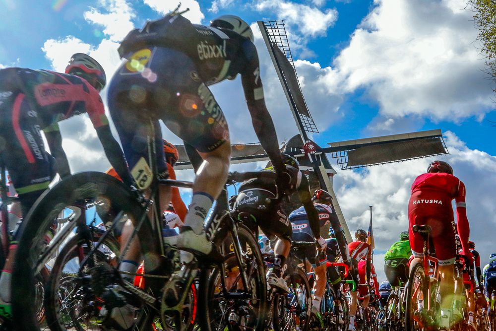 The peloton passes a windmill during Amstel Gold race