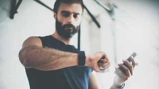 Man looking at his fitness watch in the gym