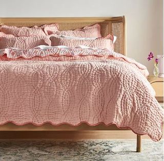 A pink quilt and pillowcases on a double bed