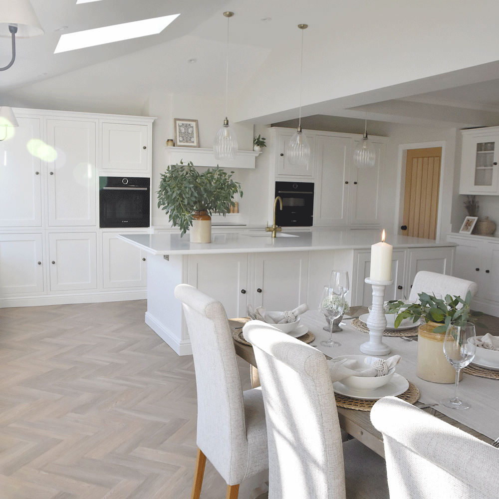 White kitchen and dining area with candle and greenery
