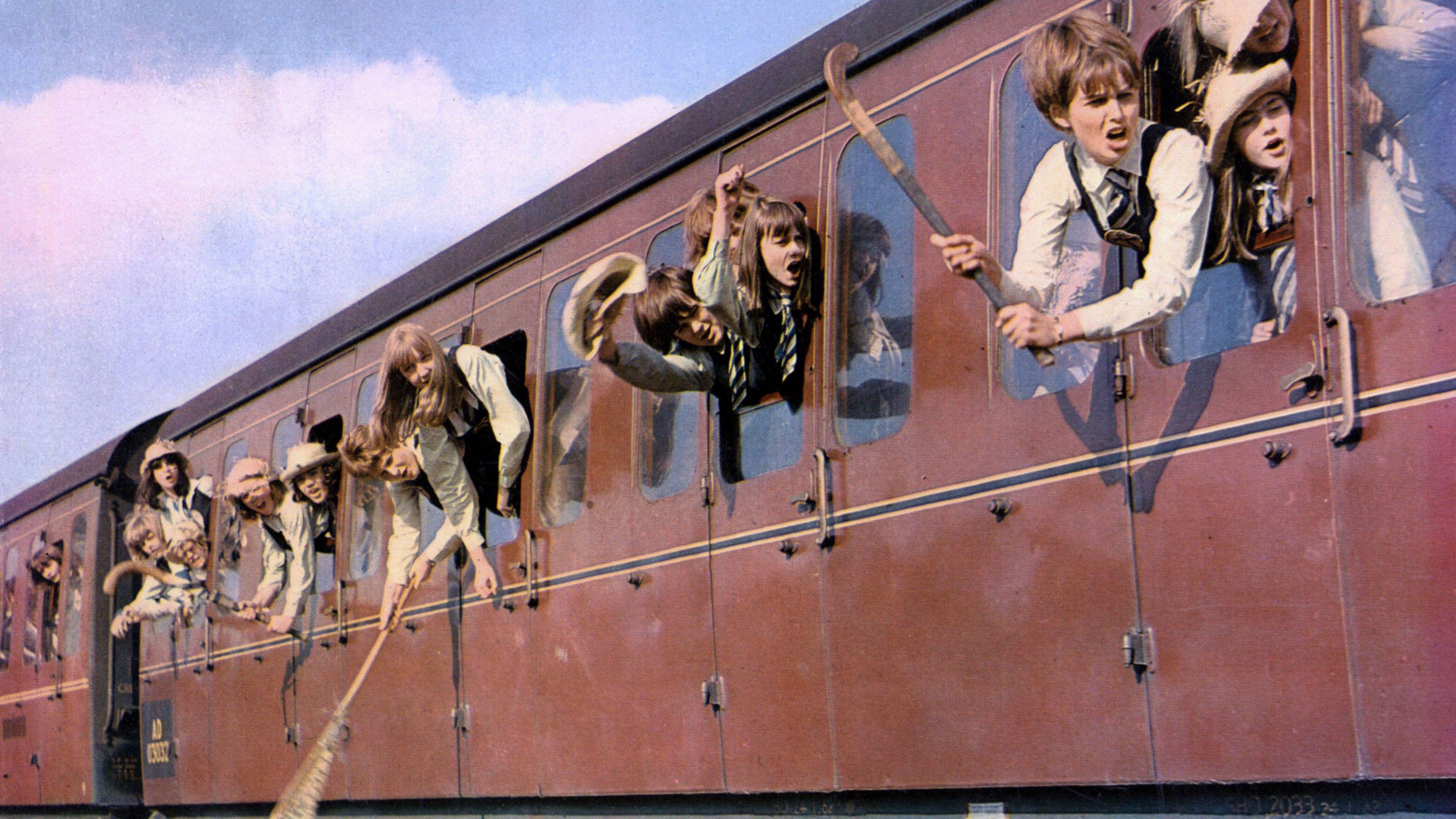 Children brandishing hockey sticks on a red train