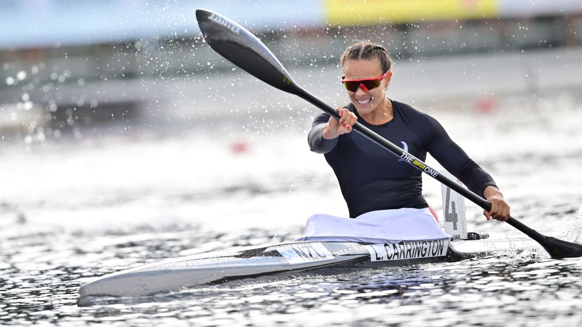 Lisa Carrington, in a black top and mirrored sunglasses, races her canoe ahead of the 2024 Paris Olympic Games Canoe Sprint. 