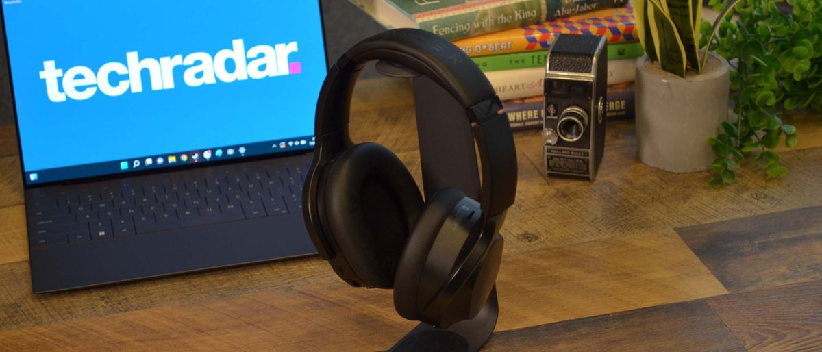 A Razer Barracuda Pro on a headset stand in front of a computer with the techradar logo on it