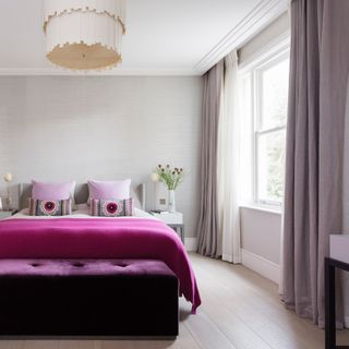 grey bedroom with purple bedding and ottoman