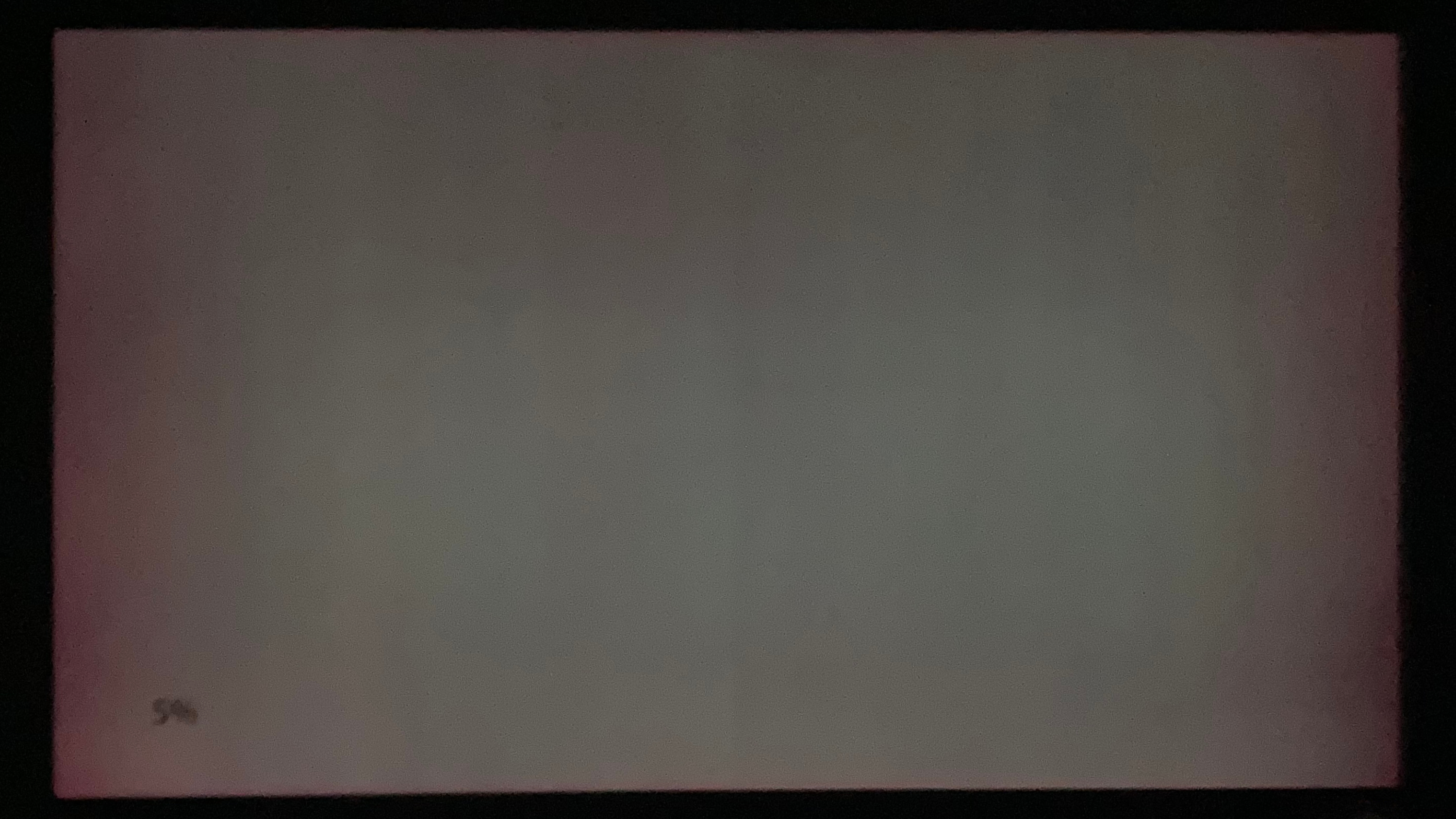 A blurry, under-exposed image of an OLED TV displaying a 100% gray image. On the left and right sides of the screen, pink tinting takes the form of a column that stretches from the top of the display to the bottom.