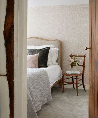 cottage bedroom with subtle william morris wallpaper and upholstered behead