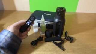 Telesin C40 Portable Smoke Machine kit laid out on a wooden desk with a remote held in a hand