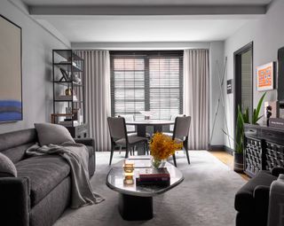 Living room with gray couch, dining table and chairs, wood floor and gray rug