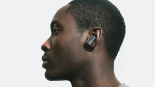Status Between 3ANC earbuds worn by a man in profile, on white background