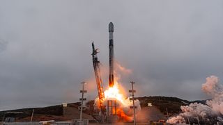a white and black rocket lifts off into overcast cloudy skies