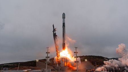 a white and black rocket lifts off into overcast cloudy skies 
