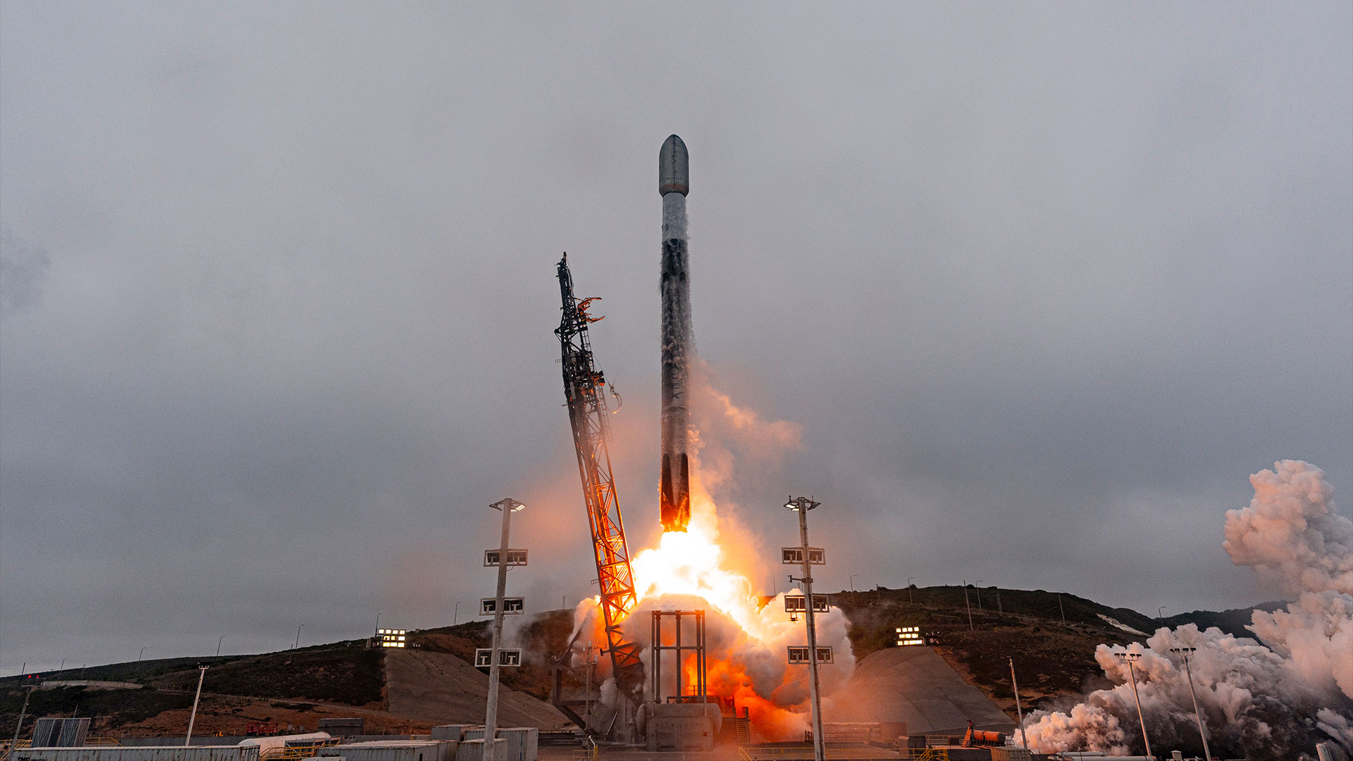 a white and black rocket lifts off into overcast cloudy skies 