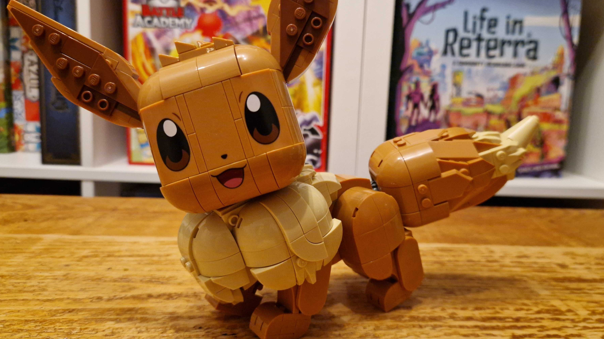 Lego Eevee on a wooden table in front of shelves filled with board games