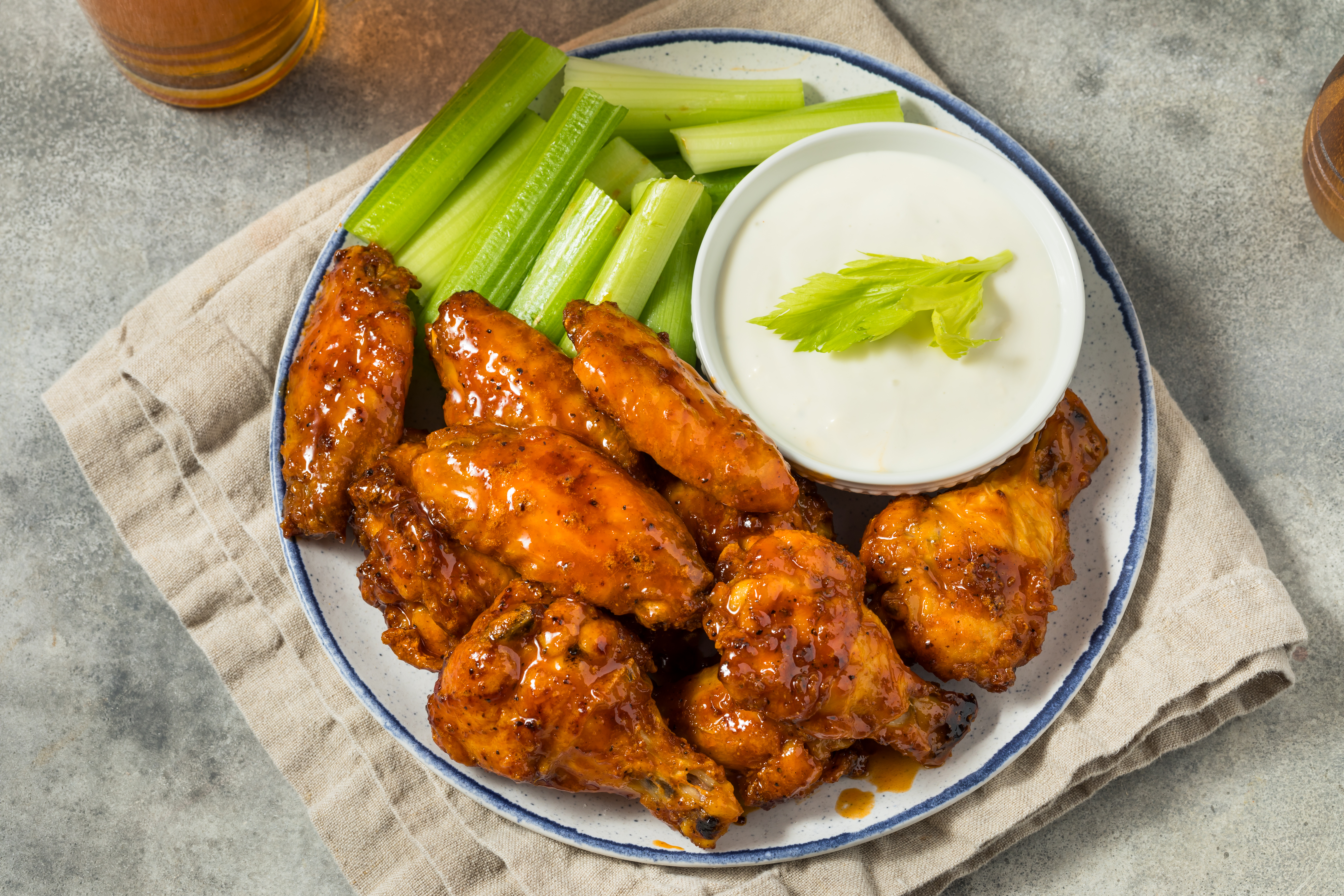A plate of Buffalo wings with celery sticks and ranch dressing