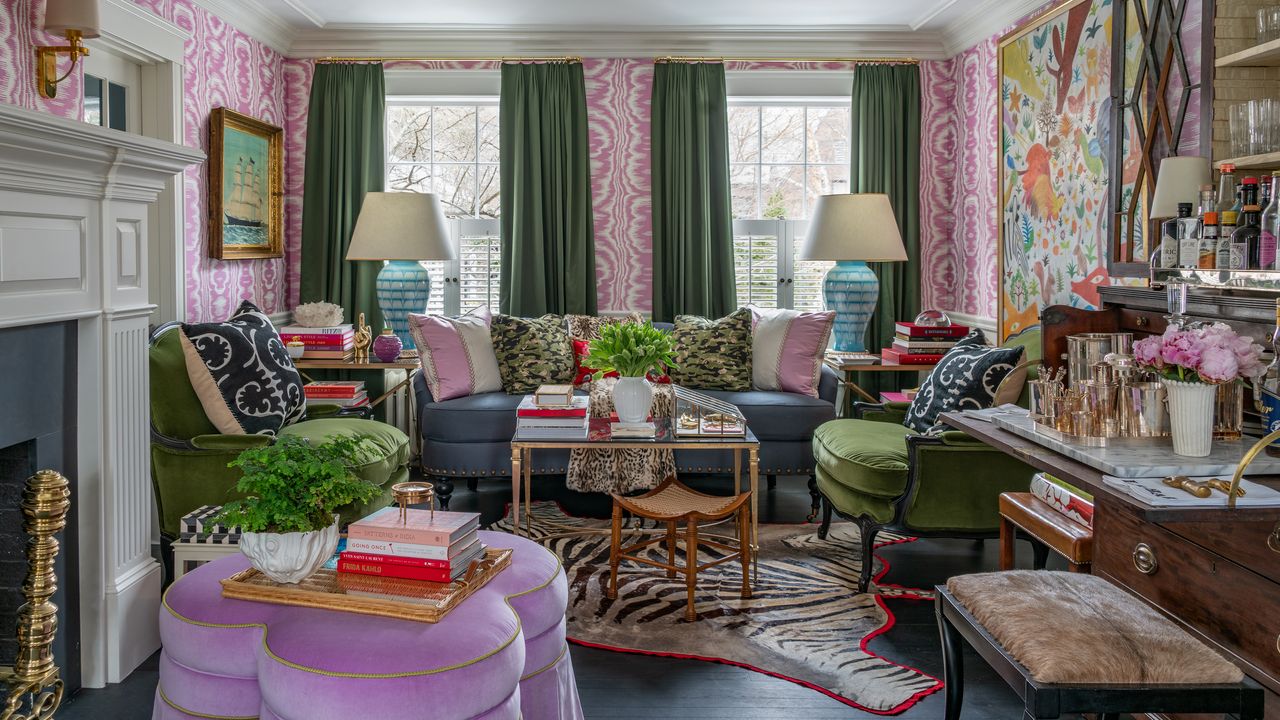 A living room with pink and white wallpaper, green curtains, artwork and an eclectic mix of multicolored wallpaper in a maximalist style