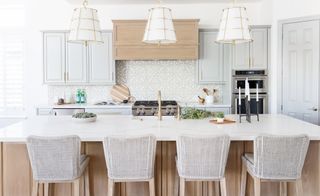 Kitchen with island and barstools with wood detail, white cabinets, stove and patterned backsplash