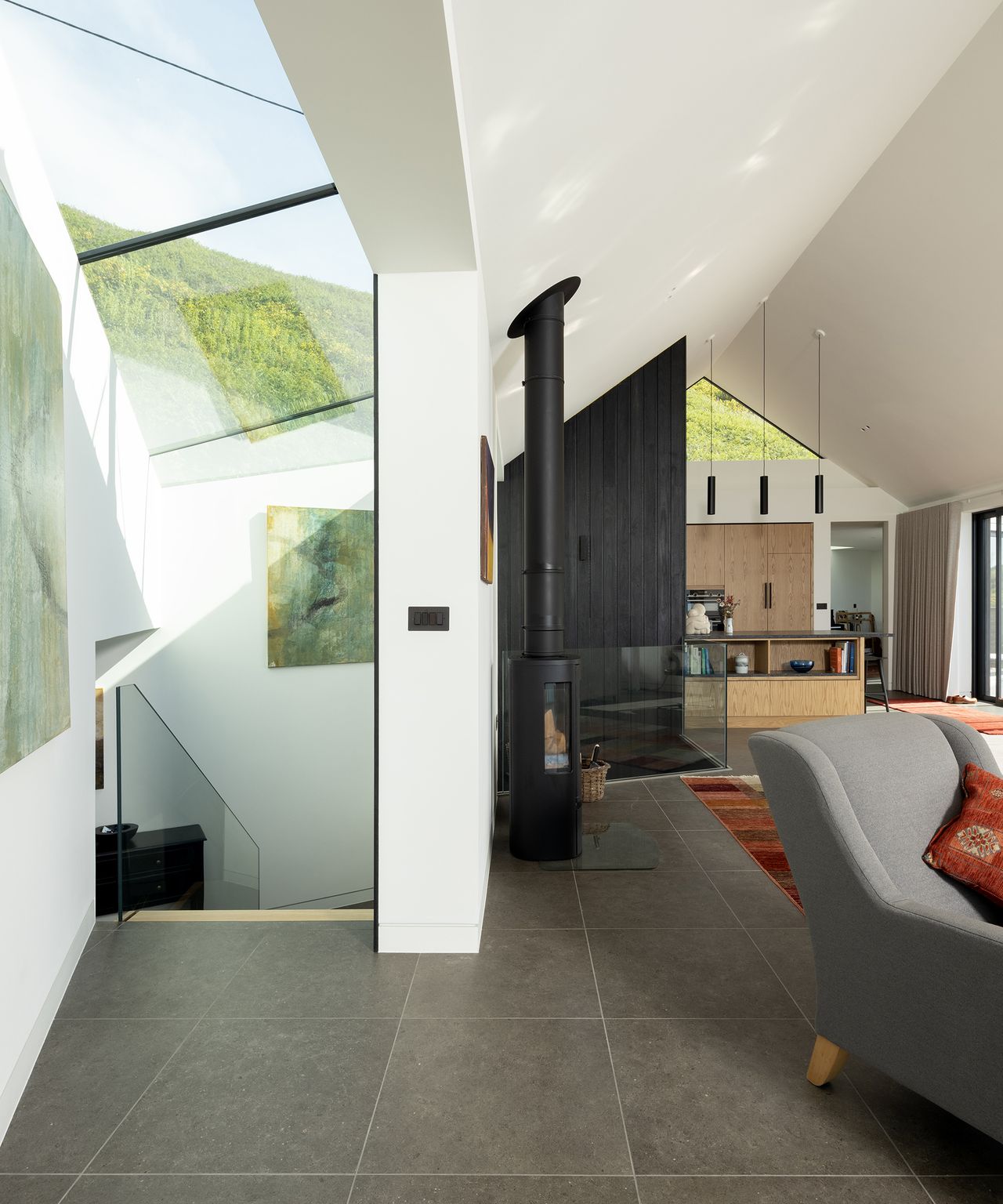 A staircase leading downstairs with a lot of ceiling glazing. It leads off an open plan living and kitchen area