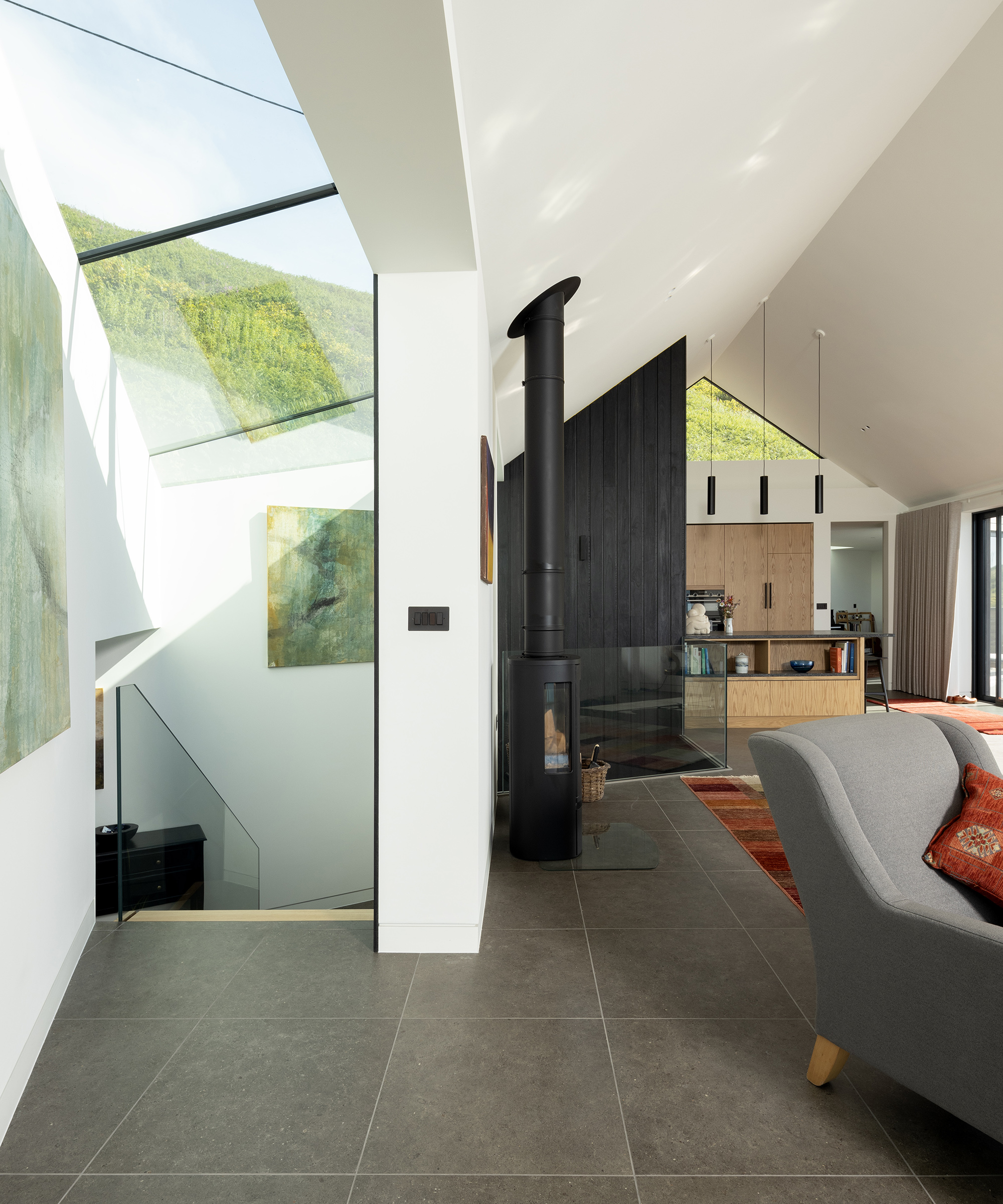 A staircase leading downstairs with a lot of ceiling glazing. It leads off an open plan living and kitchen area