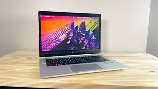 An HP EliteBook x360 1030 G2 running Fedora Linux on a wood table with the lid open