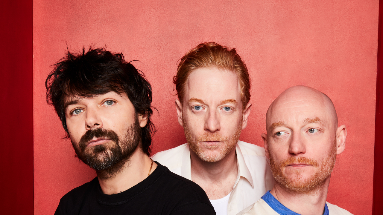 Biffy Clyro looking solemn against a red background