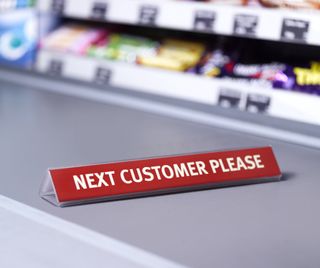 Red 'Next customer please' sign on a shop counter