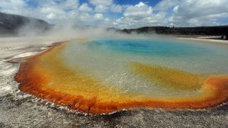 View of the 'Sunset Lake' hot spring with it's unique colors caused by brown, orange and yellow algae-like bacteria called Thermophiles, that thrive in the cooling water turning the vivid aqua-blues to a murkier greenish brown, in the Yellowstone National Park, Wyoming on June 1, 2011.