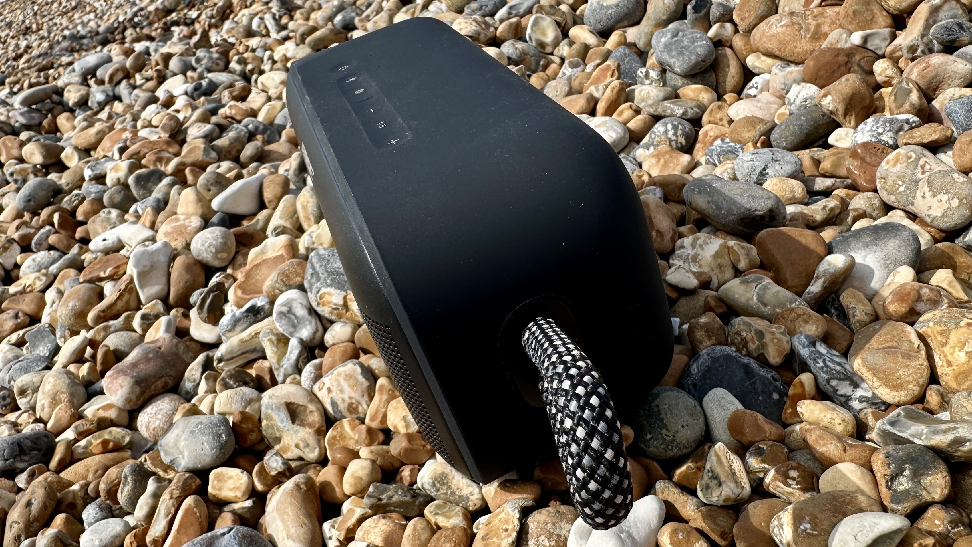 Bose SoundLink Plus on Brighton Beach pebbles, with the old pier in the background