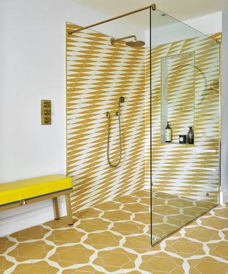 A bright yellow and white walk in shower with geometric tiles