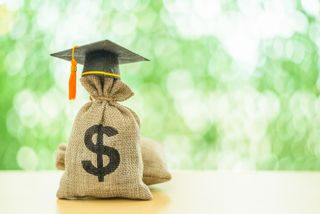 burlap bag with a dollar sign and graduation cap on it against light green background