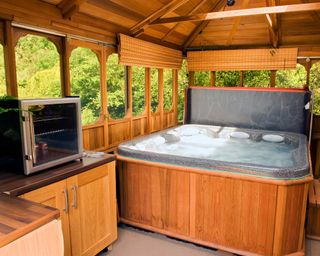 hot tub beneath wooden gazebo with blinds