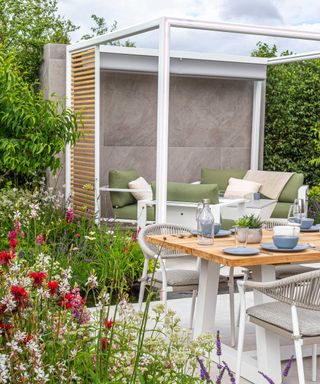modern pergola and dining set-up in 'Lower Barn Farm: The Bounce Back Garden', designed by Samuel Moore at RHS Hampton Court Palace Garden Festival 2021