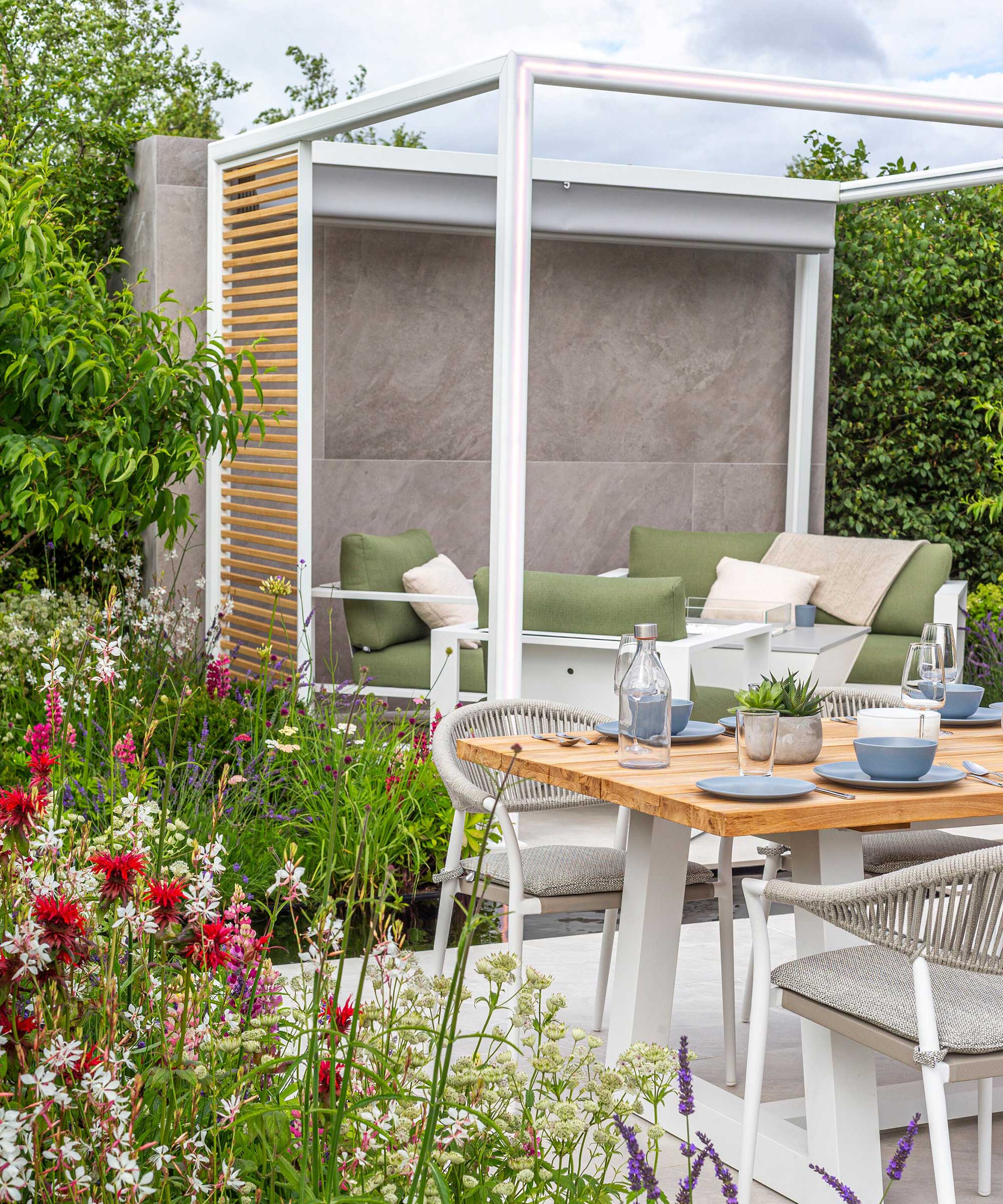 modern pergola and dining set-up in 'Lower Barn Farm: The Bounce Back Garden', designed by Samuel Moore at RHS Hampton Court Palace Garden Festival 2021