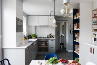 Georgia Broome kitchen: grey and white contemporary kitchen with monochrome pendant lights, white metro tile splashback and grey slate-effect floor