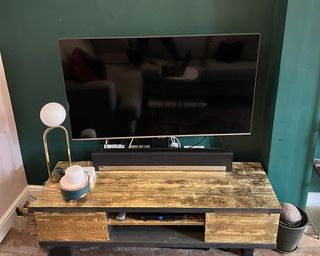 TV stand with TV against green living room wall