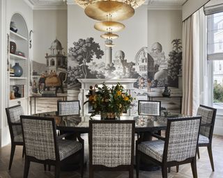 A dining table decor idea with round dark wood table, brass chandelier in a modern style, grey mural wallpaper and a floral centerpiece