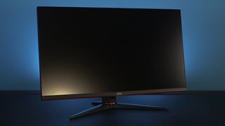 The AOC U28G2XU GAMING MONITOR front on three quarter angle with blue wall, on desk.