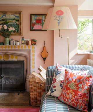 design a home that feels like you, pink living room with patterned couch and cushions, painted lampshade, painted fire surround, artwork