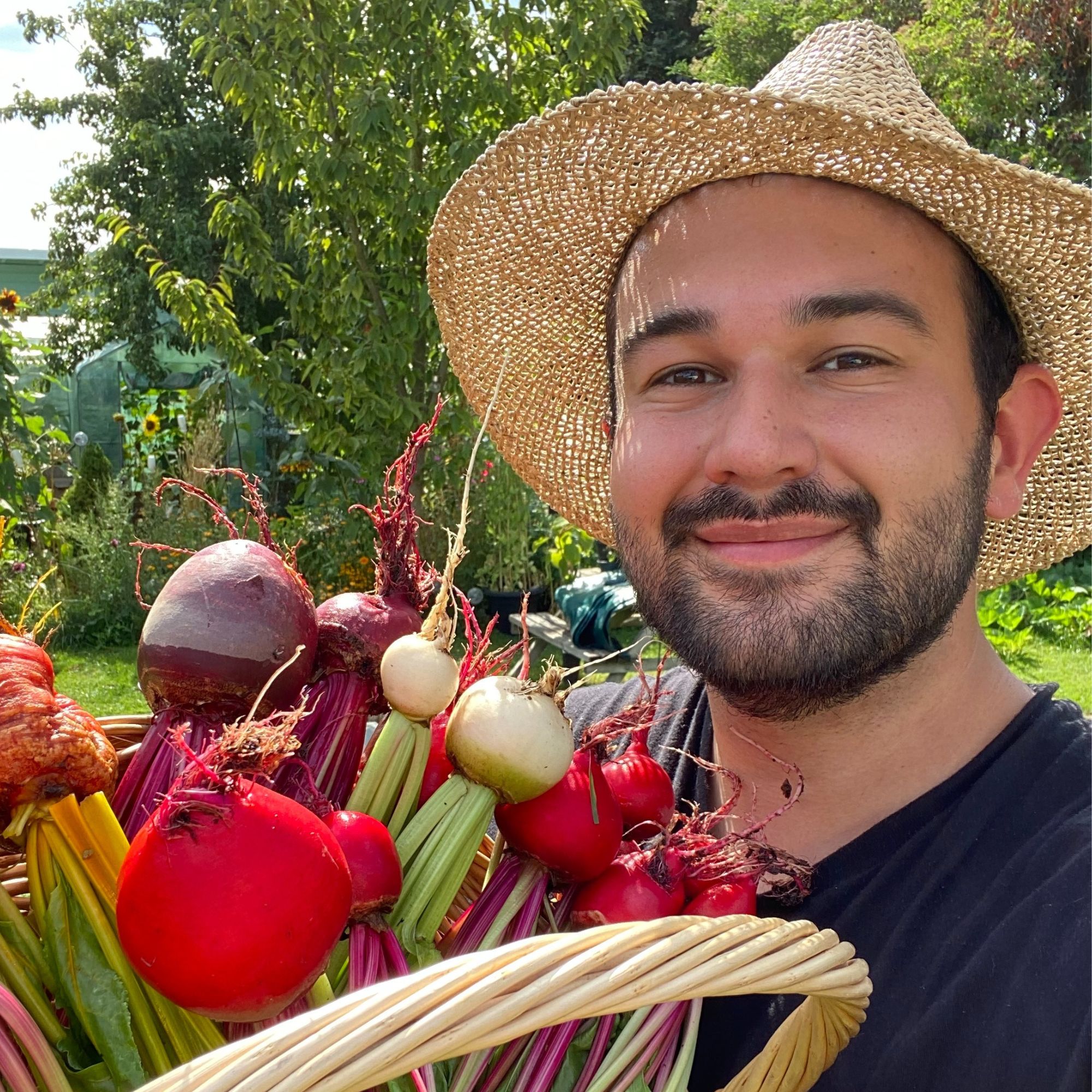Joseph Clark, of Joe's Garden fame, poses in his backyard holding a glut of produce and wearing a straw hat
