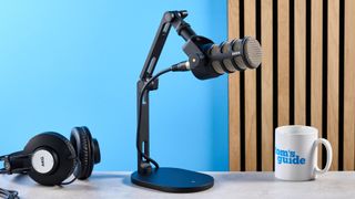 the rode podmic podcast and broadcast microphone photographed with a blue background, shown with the rode ds2 desk stand