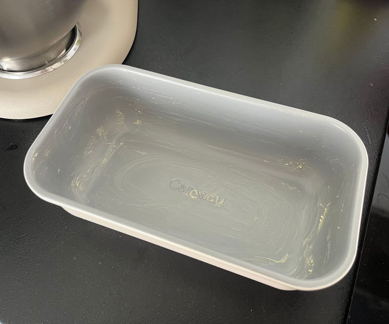 A buttered grey loaf tin viewed from above